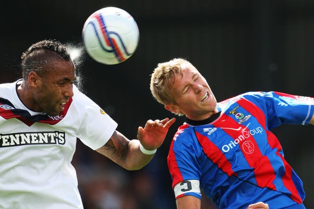 Two footballers heading the ball during a match