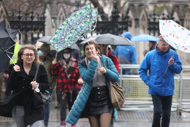 Members of the public brace themselves in the wind and wet weather in Westminster, central London