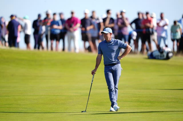 Golfer Rory McIlroy leaning on a golf club casting a shadow 