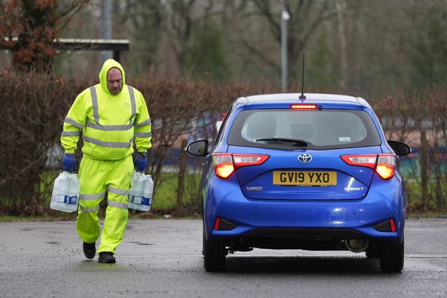 A worker carries bottled water at a water station in East Grinstead