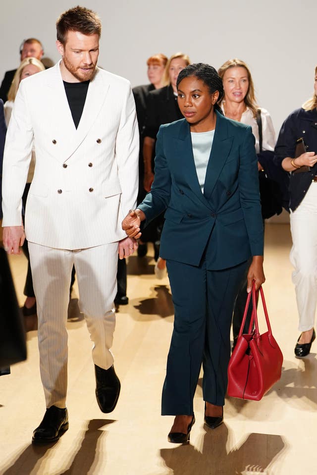 Kemi Badenoch walking and speaking to a man in a white suit