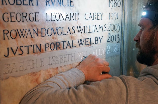 A stonemason carves the name of the new Archbishop of Canterbury Dame Sarah Mullally on to a plaque at Canterbury Cathedral 