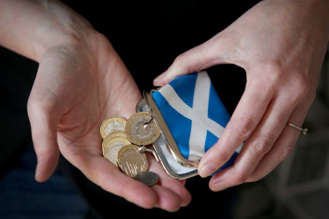 A person holding a Scottish purse and coins