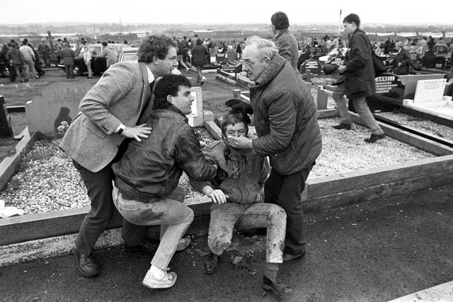 Martin McGuinness helps an injured man during the attack at Milltown Cemetery