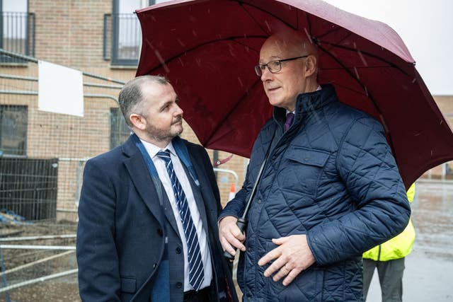 John Swinney speaking with James Ward, while sheltering under an umbrella 