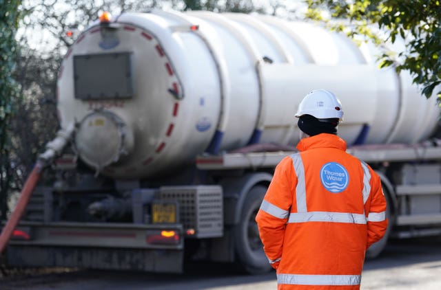 A Thames Water worker from behind in front of a tanker