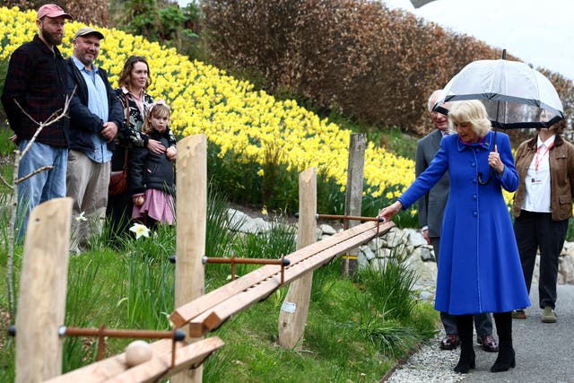 Camilla walking down a path outside, under an umbrella