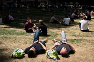 People relax in the sun in Victoria, central London