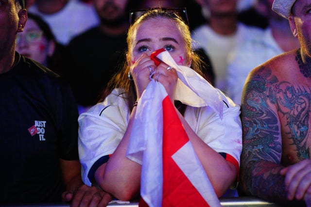 A woman clutches an England flag to her face as she watches the match