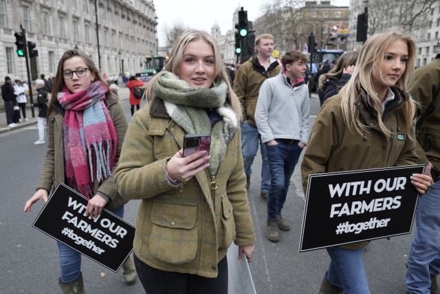 Three young women holding placards reading 'With our farmers'