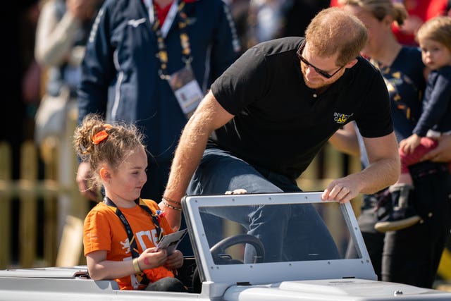 Harry with Scarlet Vroegop, four, in a toy Land Rover (Aaron Chown/PA)