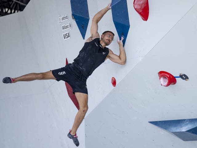 A sports climber holds on by just his hands. 