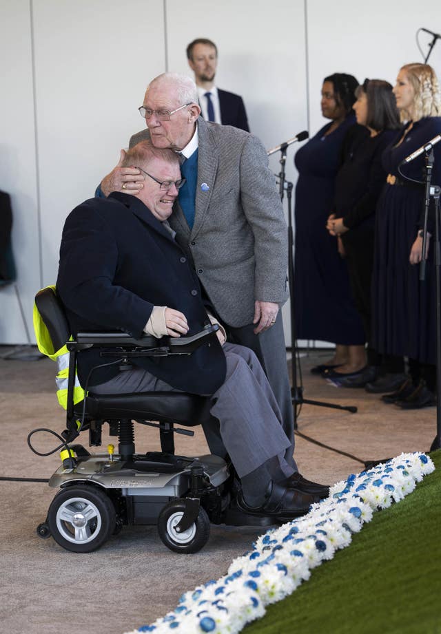 Niall Westhead, left, volunteer at Kent and Canterbury Hospital, is comforted by his father Tony as he lays a wreath during a live broadcast memorial event hosted by NHS Charities Together at the National Memorial Arboretum in Staffordshire to mark the third anniversary of the World Health Organisation declaring a global Covid-19 pandemic 