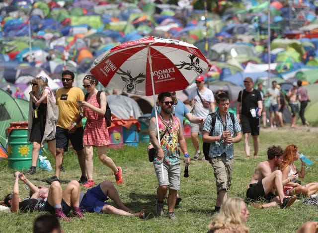 A festival goer carrying a large umbrella in the hot weather on the third day of the Glastonbury Festival at Worthy Farm in Somerset 