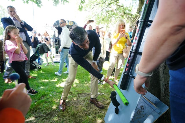 Prime Minister Rishi Sunak has a go at a 'splat the rat' game at a village fete in Great Ayton during General Election campaigning 