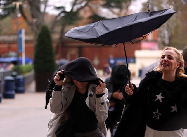 Racegoers battle the wind and rain at Ascot Racecourse on Saturday 