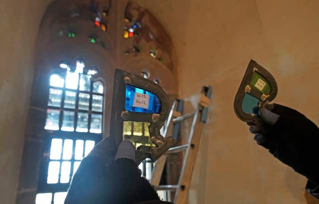 Stained glass window parts are held up to the light as restoration work is carried out (Owen Humphreys/PA)