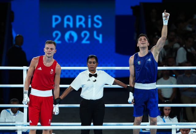 Verde with an arm in the air being crowned winner in the ring alongside Richardson