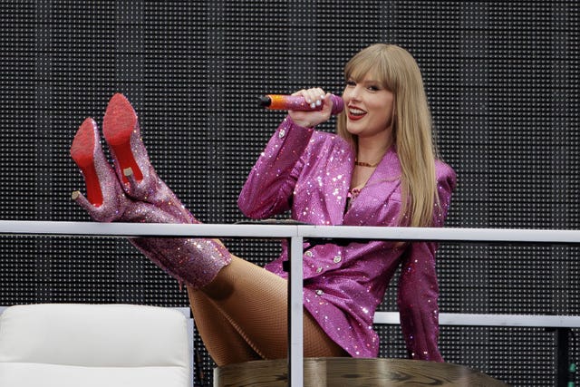 Taylor Swift on stage in pink boots and a matching sparkly coat 