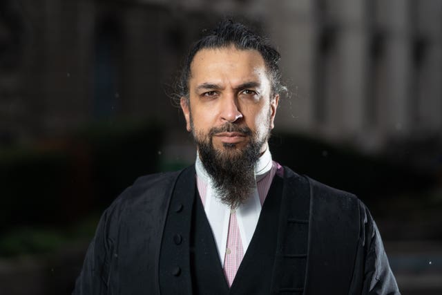 Head and shoulders of a bearded man in a black court robe