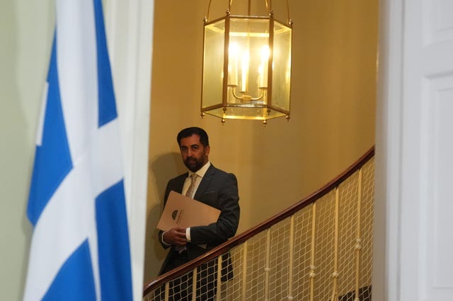 Humza Yousaf walks down stairs clutching a folder before resigning as First Minister