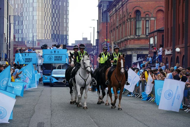 Mounted police officers patrol the route ahead of Manchester City's open-top bus parade