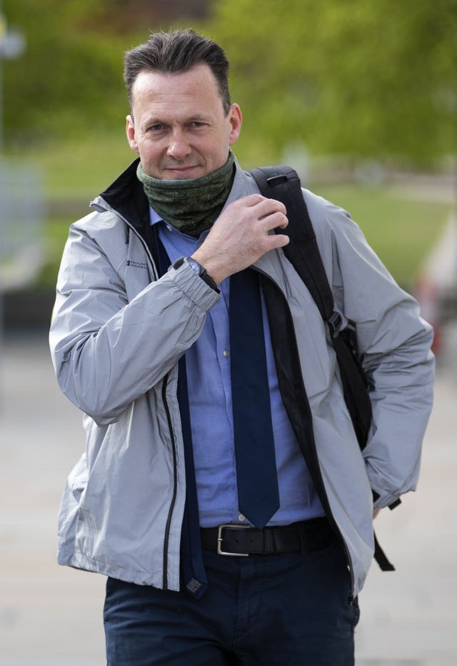 Russell Findlay wearing jacket and scarf, with bag over his shoulder