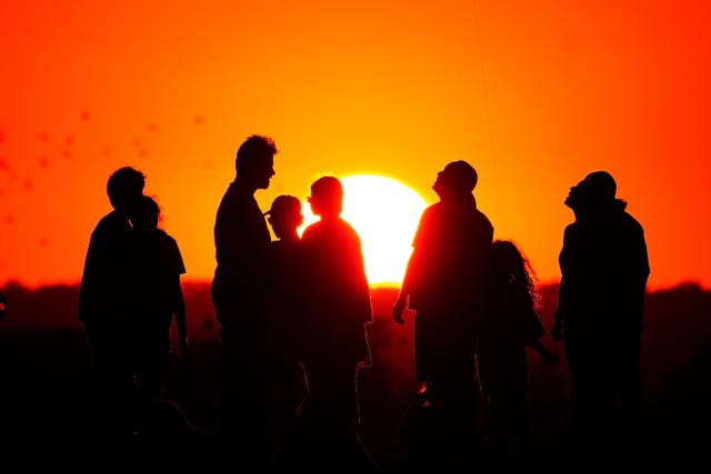 A crowd of people watch the setting sun