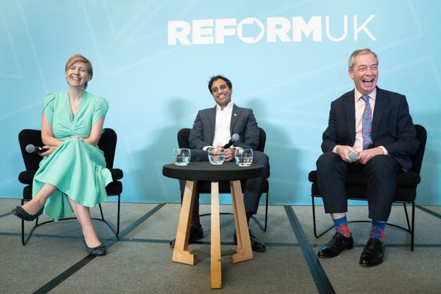 Andrea Jenkyns, left, Zia Yusuf, centre and Nigel Farage sitting in chairs around a table with glasses of water on it