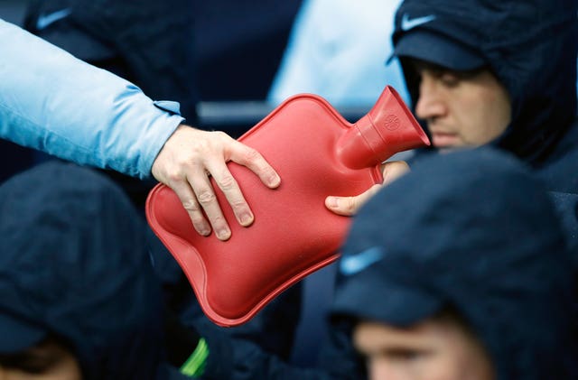 A hot water bottle is passed around on the Manchester City bench 