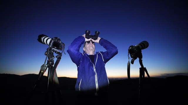 A man looking at the night sky through binoculars