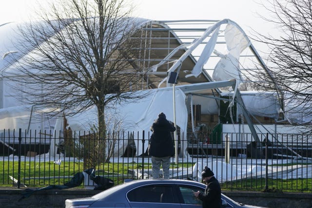 A member of the public looks on at a structure that is missing its roof