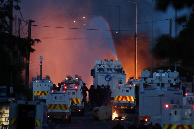 Police fire a water cannon towards rioters after they set fire to wheelie bins and removed a garden fence to use as a shield against the water cannon on Antrim Road, at the Sandyknowes roundabout in Newtownabbey