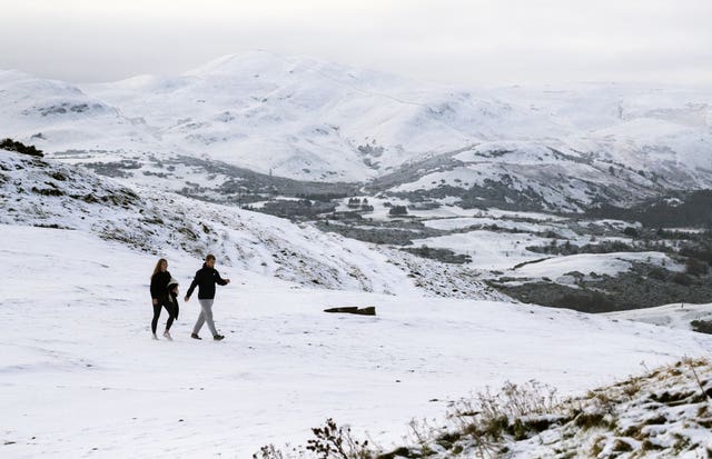 A couple walk through the snow in Holyrood Park, Edinburgh