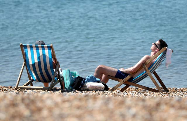 People enjoy the warm weather on the beach in Brighton, East Sussex (Gareth Fuller/PA)