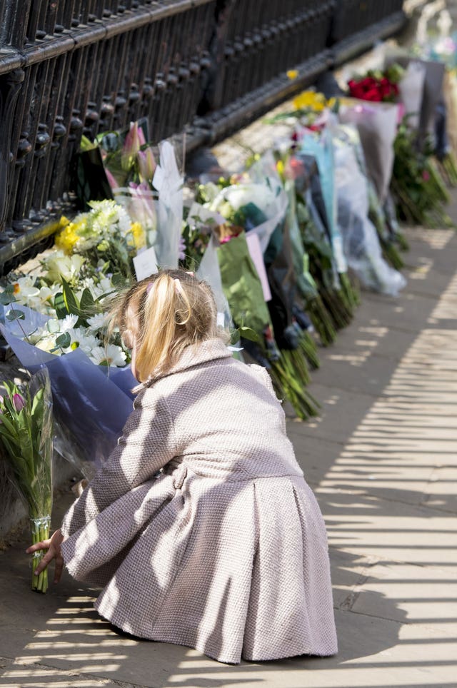 Two-year-old Maggie lays a floral tribute outside Buckingham Palace