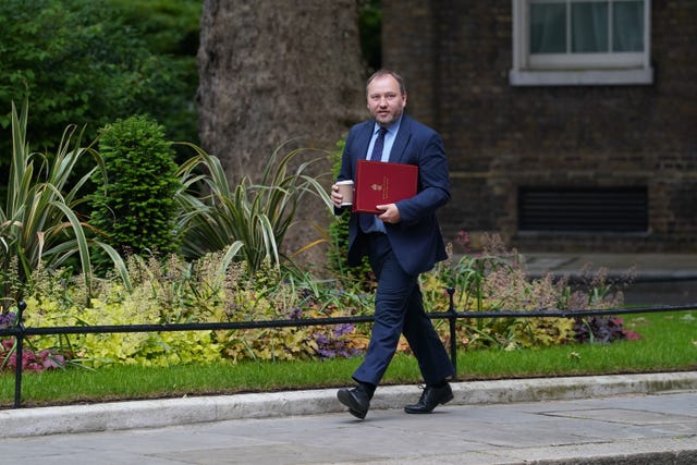Ian Murray walking along Downing Street, carrying his red ministerial folder and a drink