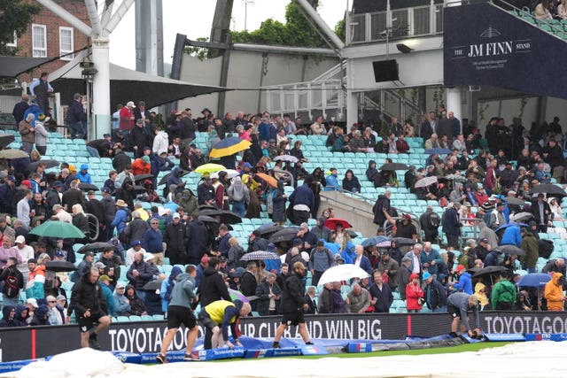 Spectators take cover under umbrellas as rain stops pla