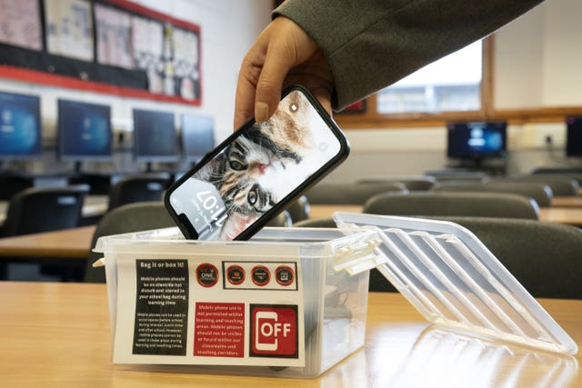 Student putting phone in box in school