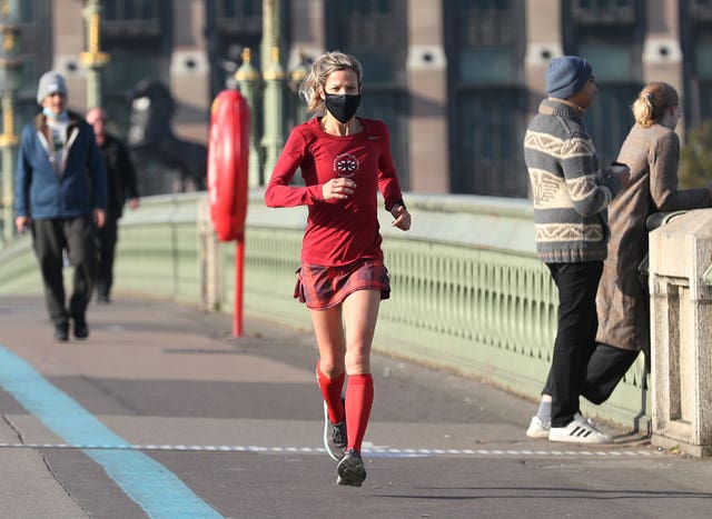 A woman wearing a face mask jogging on Westminster Bridge in London