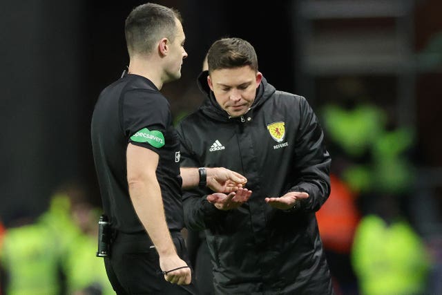 Referee Don Robertson (left) passes an object that was thrown from the crowd towards Celtic’s Arne Engels to a stadium official 