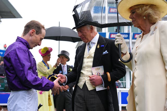 Jockey Rowan Scott is presented with a cap by the King