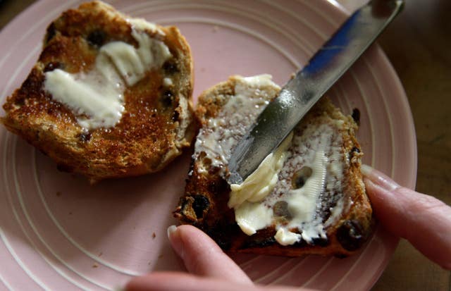 Butter being spread on a hot cross bun