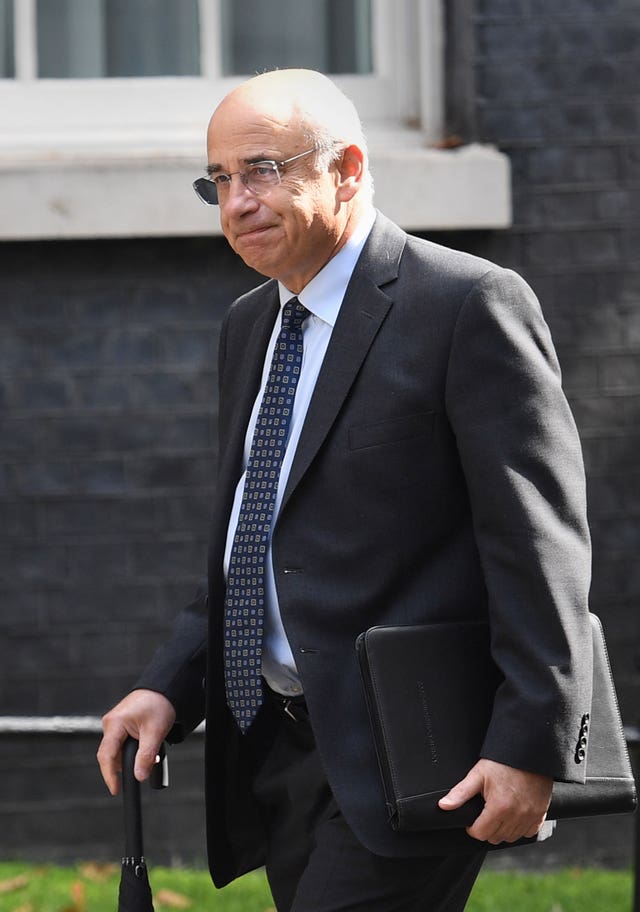 Sir Brian Leveson arriving at Downing Street holding an umbrella in one had and a notepad in his other