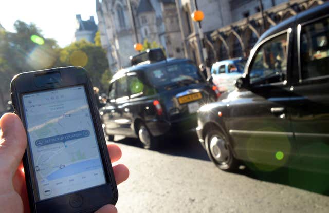 A man holds a smartphone displaying the Uber app (Anthony Devlin/PA)