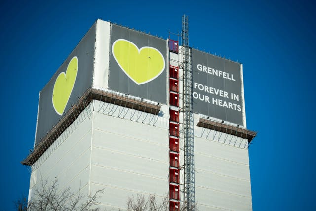 A covering on Grenfell Tower featuring a large green heart accompanied by the words 'forever in our hearts' 