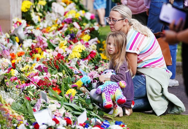 Rachel Elwood and her daughter Robyn, five, from Lisburn, look at flowers at the gates of Hillsborough Castle, Co Down