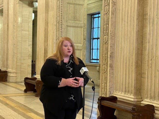 Naomi Long speaking into microphones at Stormont