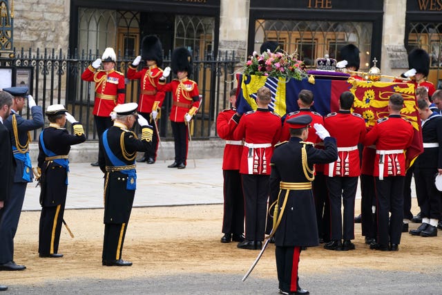 Members of the armed forces and the Royal Family greet the Queen's coffin
