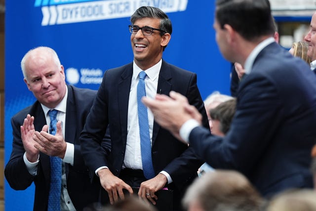 Prime Minister Rishi Sunak is applauded by Andrew RT Davies, Leader of the Welsh Conservatives (left) during a visit to a bathroom supply company near Rhyl